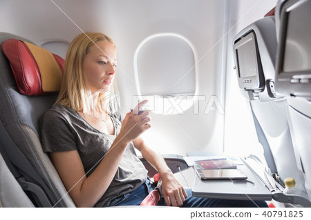 Woman drinking coffee on commercial passengers airplane during flight. 40791825