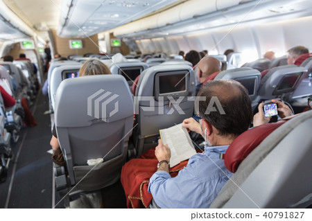Interior of large commercial airplane with passengers on their seats during flight. Interior of large commercial airplane with passengers on their seats during flight. 40791827