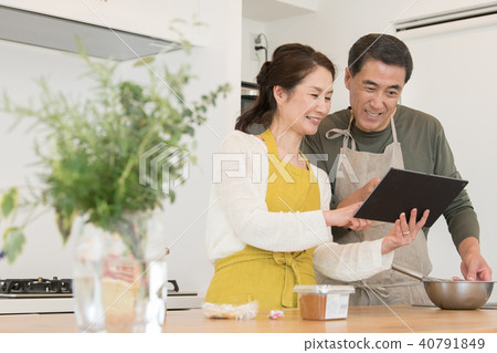 通過看食譜烹調的中間資深夫婦 通過看食譜烹調的中間資深夫婦 40791849