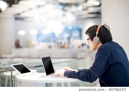 Asian businessman listening to music while working Asian businessman listening to music while working 40798287