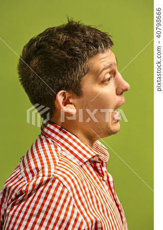 The young attractive man looking suprised isolated on green 40798666