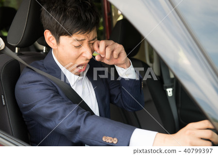 A young businessman yawning while driving A young businessman yawning while driving 40799397