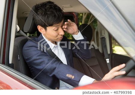 A young businessman who gets sleepy while driving 40799398