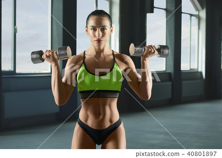 Woman bodybuilder lifting metallic dumbbells. 40801897
