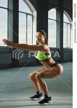 Attractive woman with athletic body doing sitting up and downs in spacy gym. Attractive woman with athletic body doing sitting up and downs in spacy gym. 40801898