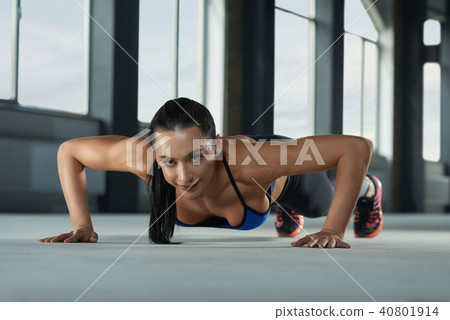 Young sporty girl with athletic body doing push ups on the gym floor. Young sporty girl with athletic body doing push ups on the gym floor. 40801914