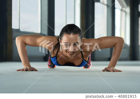 frontview of young sporty girl with athletic body doing push ups on gym floor. frontview of young sporty girl with athletic body doing push ups on gym floor. 40801915