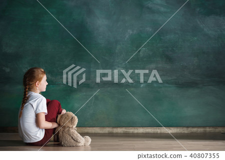 Little girl with teddy bear sitting on floor in empty room. Autism concept 40807355