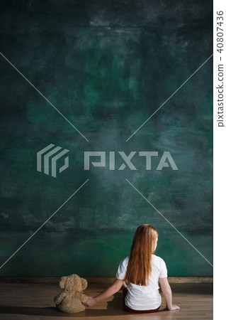 Little girl with teddy bear sitting on floor in empty room. Autism concept Little girl with teddy bear sitting on floor in empty room. Autism concept 40807436