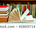 Open book, stack of hardback books on table. Top view. 40809714
