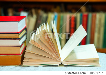 Open book, stack of hardback books on table. Top view. 40809714