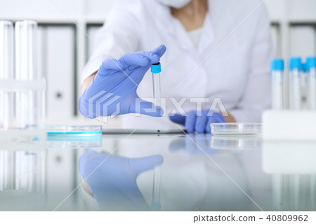 Close-up of professional female scientist in protective eyeglasses making experiment with reagents 40809962