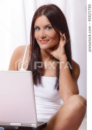 Young woman on bed using laptop Young woman on bed using laptop 40825780