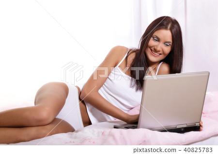 Young woman on bed using laptop Young woman on bed using laptop 40825783