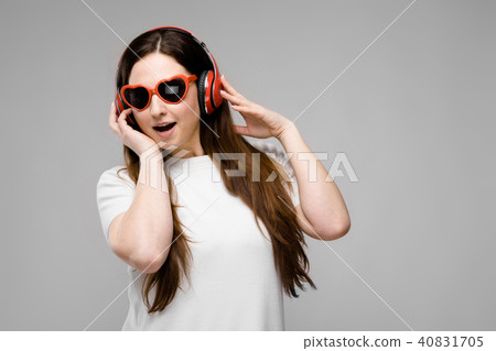 Portrait of emotional beautiful happy plus size model in headphones and sunglasses standing in Portrait of emotional beautiful happy plus size model in headphones and sunglasses standing in 40831705