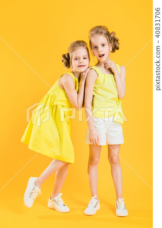 The girls of the twins stand together on a yellow background. The girls of the twins stand together on a yellow background. 40831706