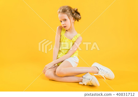 A teenage girl is sitting on a yellow background. A teenage girl is sitting on a yellow background. 40831712
