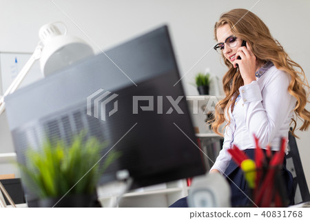 A beautiful young girl sat down on the table in the office and was talking on the phone. Before the A beautiful young girl sat down on the table in the office and was talking on the phone. Before the 40831768