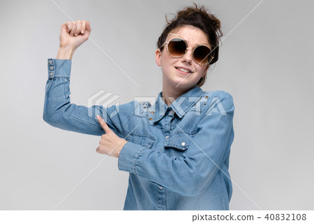 Young brunette girl in black glasses. Cat glasses. The hair is gathered in a bun. The girl points a 40832108