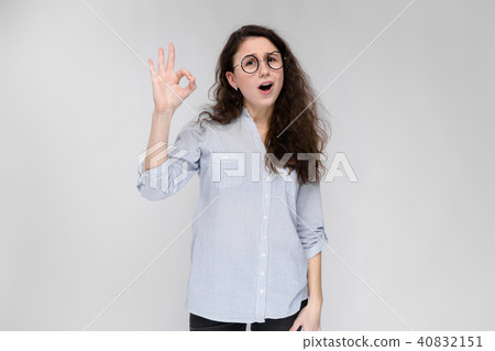 Portrait of a young girl in glasses. Beautiful young girl on a gray background. The girl shows the 40832151