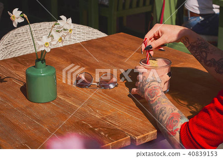 Woman is holding delicious fresh strawberry in glass transparent mugon the white wood table. 40839153