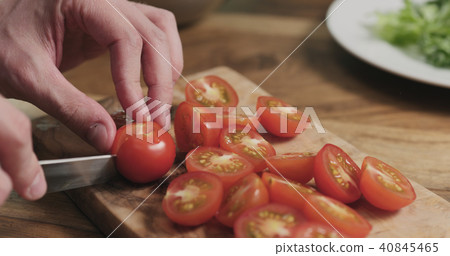 man hands slicing cherry tomato on wooden board man hands slicing cherry tomato on wooden board 40845465
