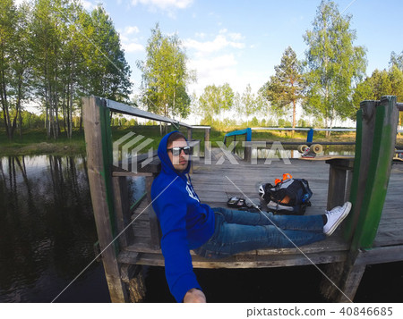 The young man makes a selfie sitting on the pier The young man makes a selfie sitting on the pier 40846685