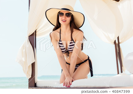 Woman enjoying her beach vacation lounging in sun tent 40847399