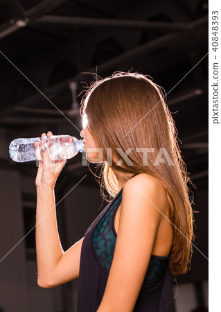 Fitness young woman drinking water in the gym. Muscular woman taking break after exercise 40848393