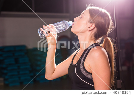 Fitness young woman drinking water in the gym. Muscular woman taking break after exercise 40848394