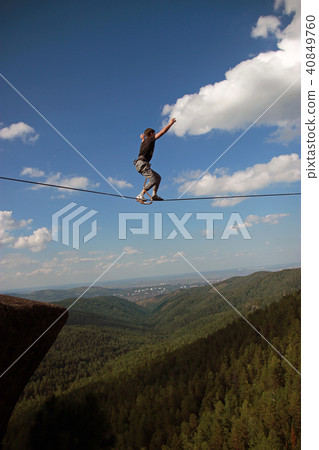 A young man ropewalker balancing over the abyss. A young man ropewalker balancing over the abyss. 40849760