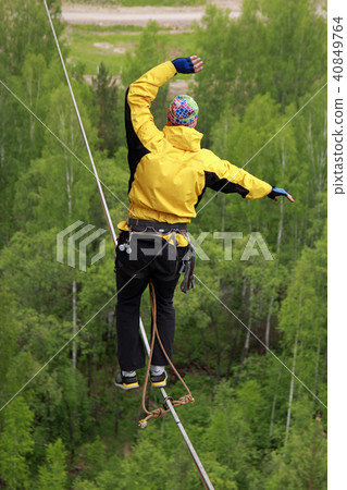 A young man ropewalker balancing over the abyss. A young man ropewalker balancing over the abyss. 40849764