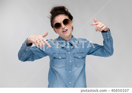 Young brunette girl in black glasses. Cat glasses. The hair is gathered in a bun. The girl shows 40850107