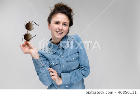 Young brunette girl holding glasses in her hand. Cat glasses. The hair is gathered in a bun. 40850111