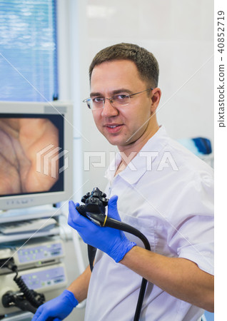 Proctologist holding an anoscope against a proctological chair. In the hospital Proctologist holding an anoscope against a proctological chair. In the hospital 40852719