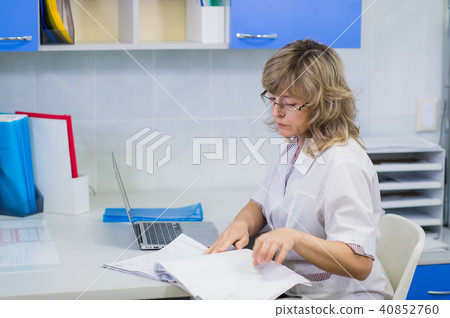 Happy senior doctor with clipboard at hospital reception 40852760