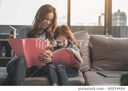 Happy mom and daughter holding albums and smiling Happy mom and daughter holding albums and smiling 40854484