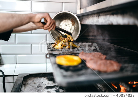 Male cook prepares grilled potato Male cook prepares grilled potato 40854822