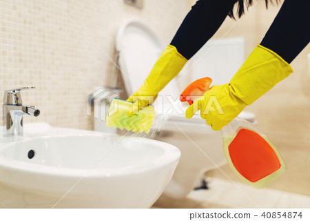 Maid cleans the bidet with a cleaning spray 40854874