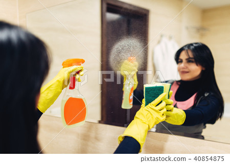 Housemaid cleans the mirror with a cleaning spray 40854875