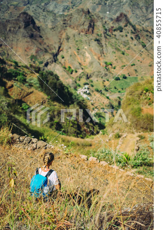 Hiker woman take a rest on mountain slope. Sitting on sharp summit and enjoy spectacular view 40855715