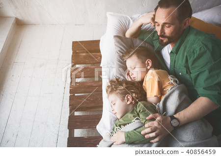 Smiling parent hugging sleeping sons 40856459