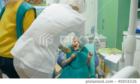 Child with a mother at a dentist's reception. The girl lies in the chair, behind her mother. The 40858326