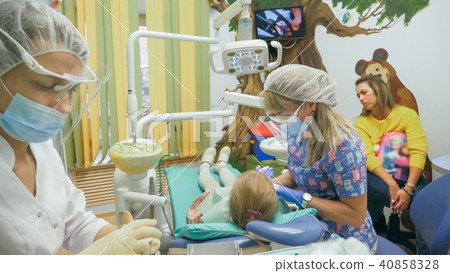 Child with a mother at a dentist's reception. The girl lies in the chair, behind her mother. The 40858328