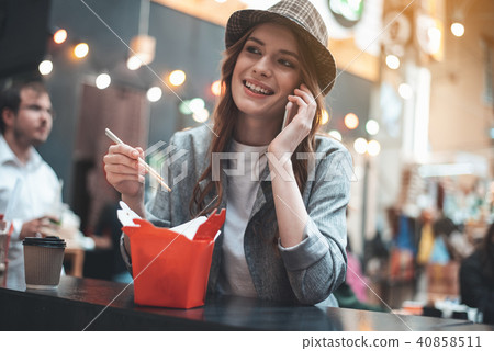 Pretty woman is enjoying talking on smartphone during meals 40858511