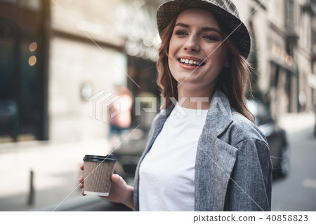 Smiling young woman with cup of coffee in the street Smiling young woman with cup of coffee in the street 40858823