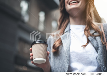 Young cheerful woman is holding cup of coffee Young cheerful woman is holding cup of coffee 40858840