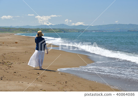 一個女人戴著草帽在沙灘上走在沙灘上的白色連衣裙的肖像 一個女人戴著草帽在沙灘上走在沙灘上的白色連衣裙的肖像 40864086