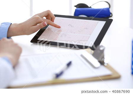 Woman doctor using tablet computer while sitting at the desk in hospital closeup. Cardiologist 40867690
