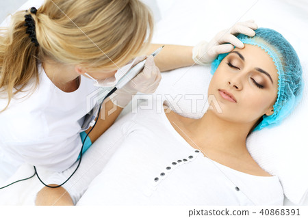 Professional beautician doing eyebrow tattoo at woman face. Permanent brow makeup in beauty salon 40868391